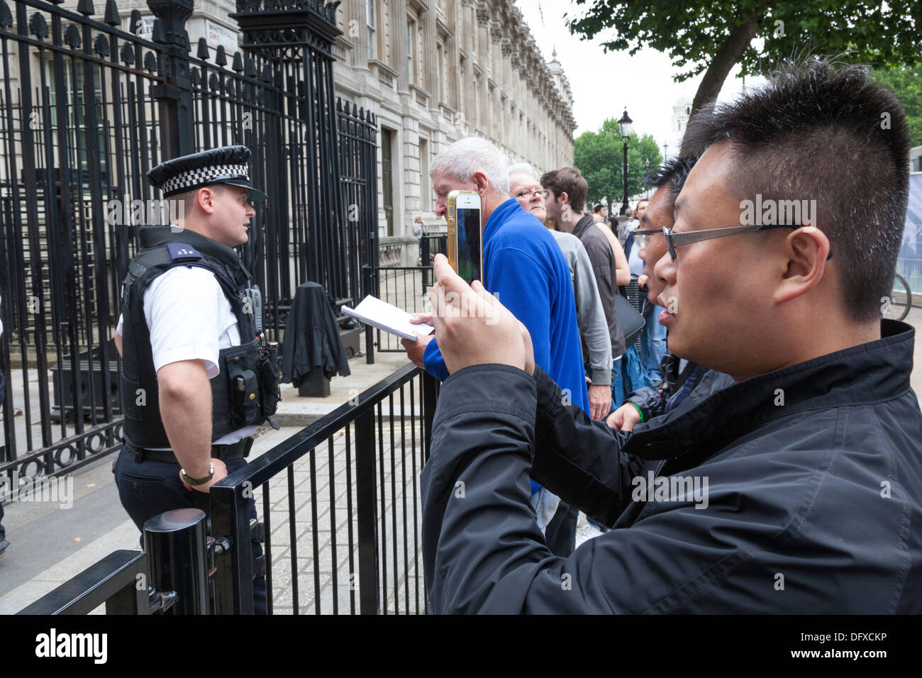 Ein Tourist nutzt sein Iphone, um ein Polizist vor Downing Street zu fotografieren. Stockfoto