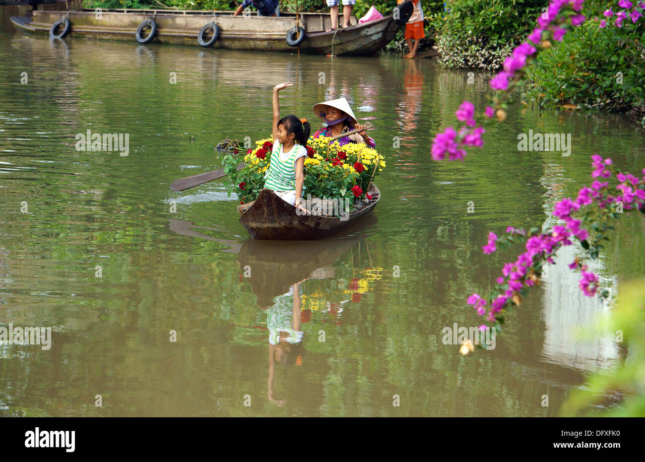 Frauen rudern das Ruderboot, um Blumentopf im Frühling auf dem Fluss am Mekong Delta, Vietnam zu transportieren Stockfoto
