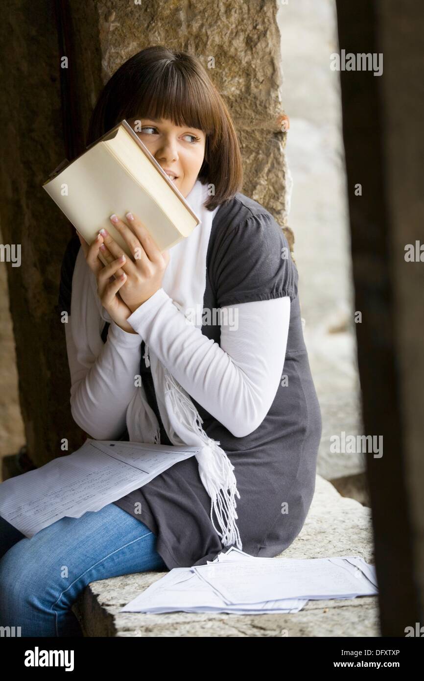 Student junge Frau verbirgt ihr Gesicht hinter einem Buch Stockfoto