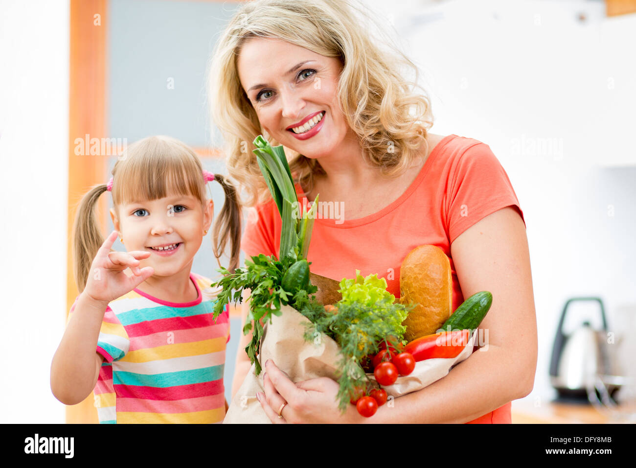 Mutter und Kind hält eine Einkaufstüte voll mit Gemüse in der Küche Stockfoto