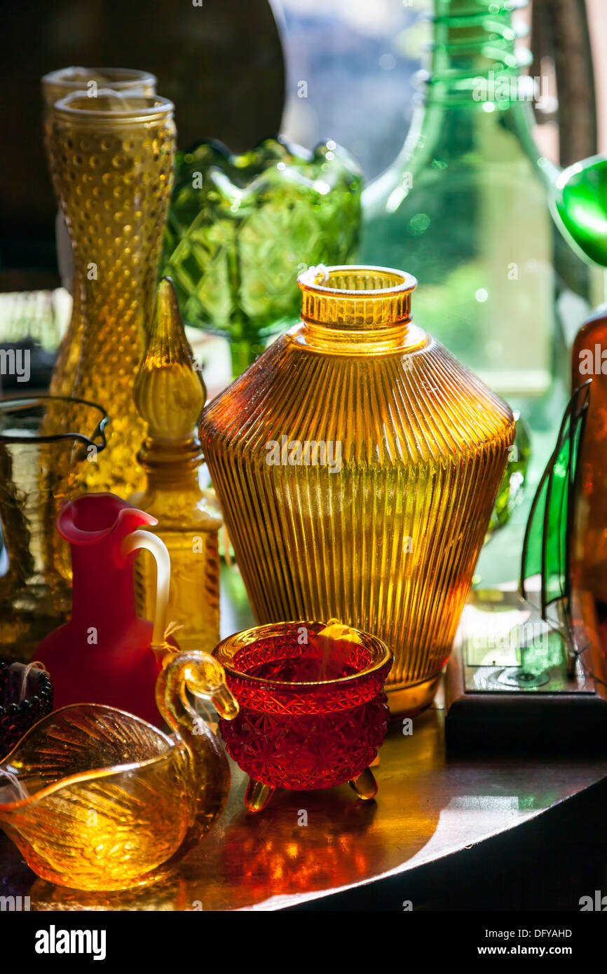 Farbige Ornamentgläser Vasen, Gläser und dekorative Figuren auf einem Tisch angeordnet. Stockfoto