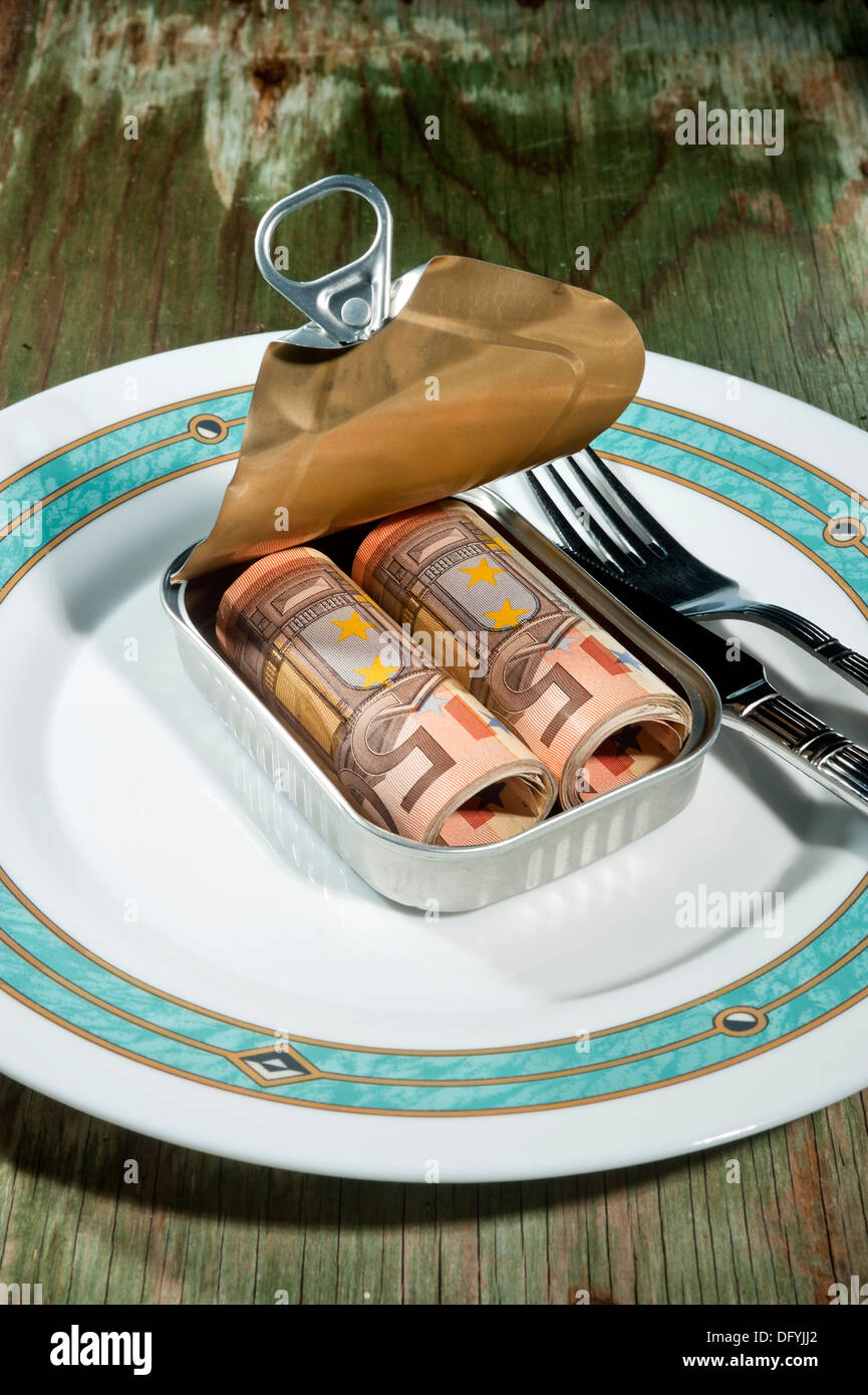 Eine Blechdose mit Geld auf einem Teller mit Besteck, platziert einen alten Holztisch Stockfoto