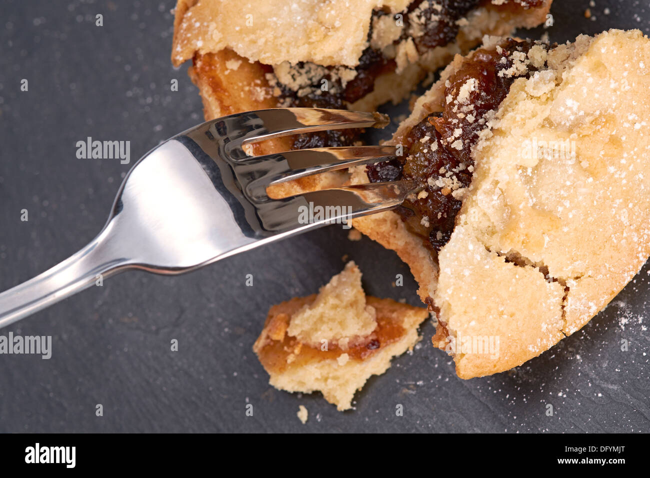 Ein Bruchgrößen Weet Weihnachten Mince Pie auf einer Tafel Kühlung Board mit einer Gabel hinein kleben. Stockfoto