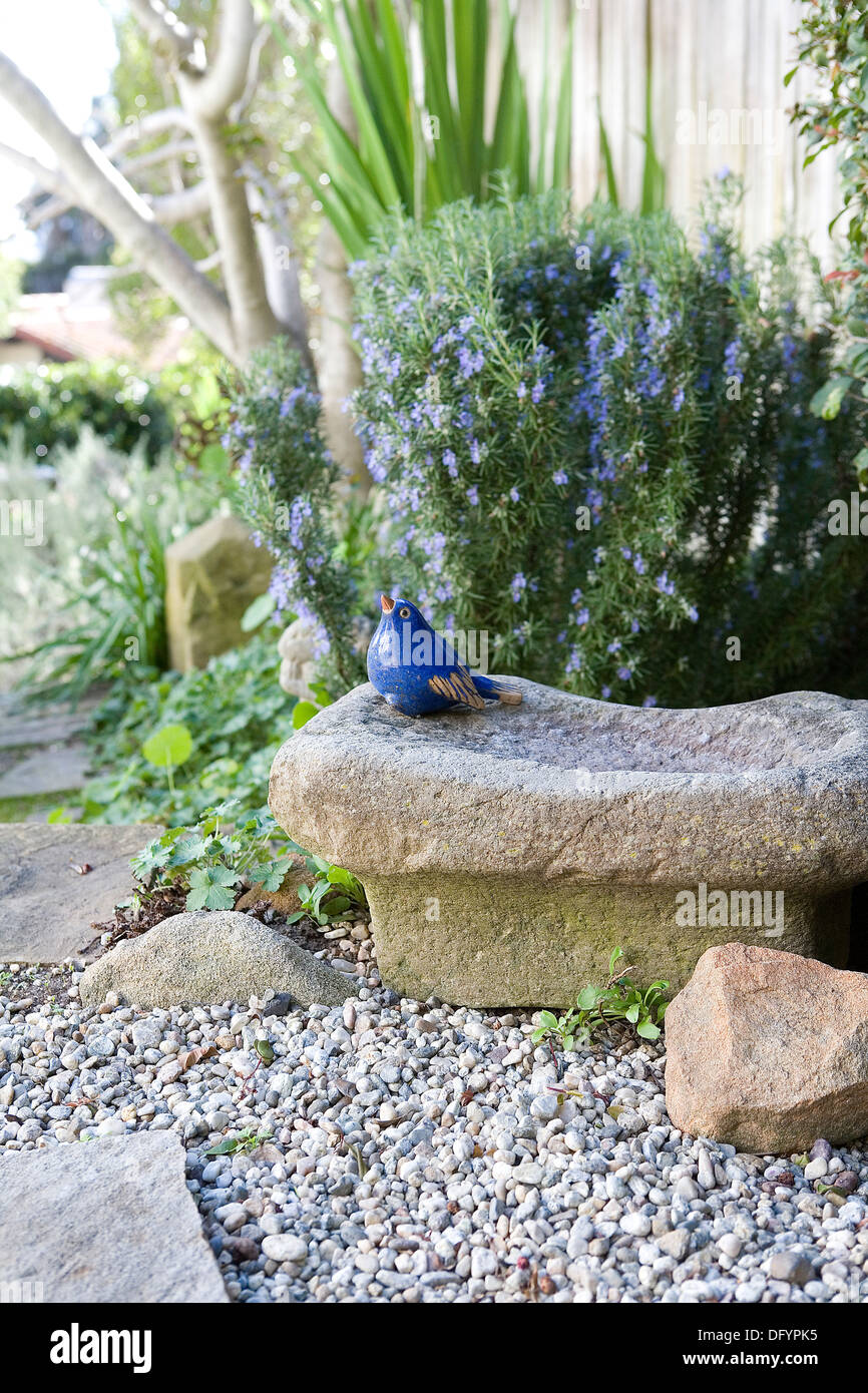 Eine kleine blaue Vogel-Statue in einem Garten Stockfoto