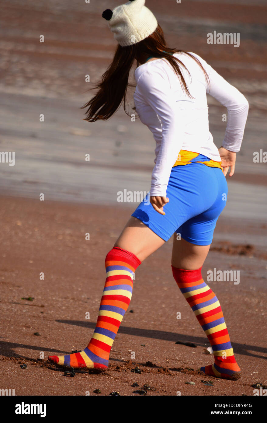 Gestreifte Socken, getragen von einem unbekannten Mädchen, am Sandstrand Stockfoto