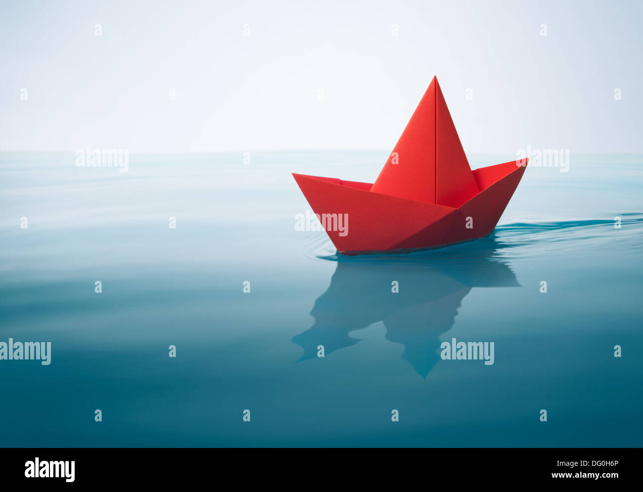 rotes Papierboot Segeln auf dem Wasser mit Wellen und Wellen Stockfoto