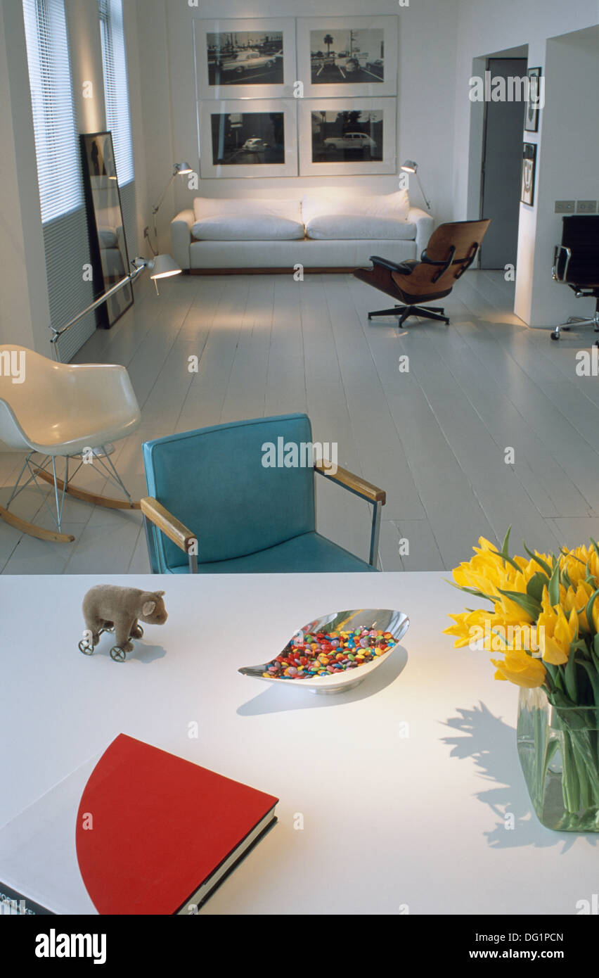 Buch und Vase mit gelben Tulpen auf weißen Tisch in moderne offene Wohnung mit weiß lackierten Boden und weißen sofa Stockfoto
