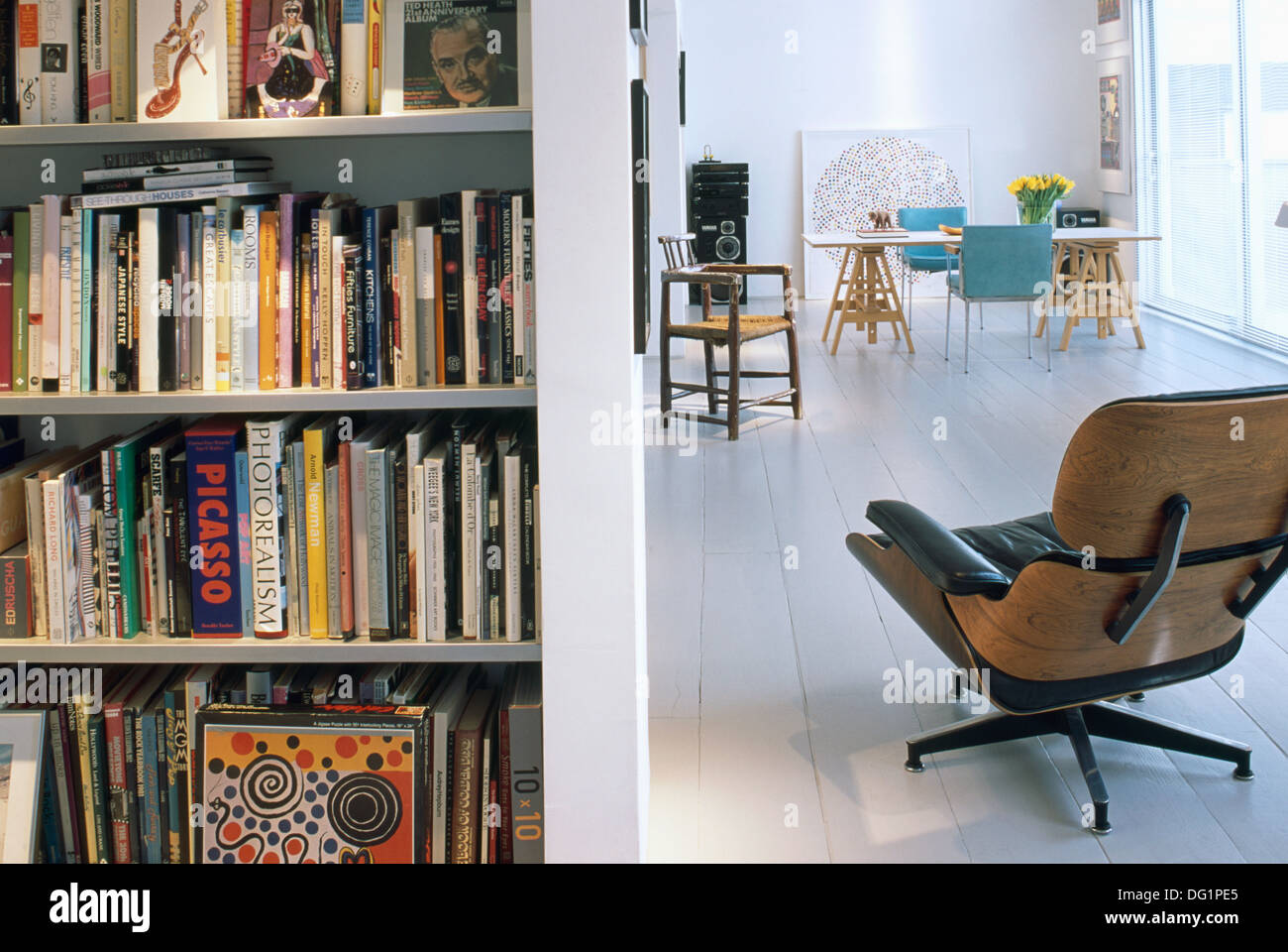 Charles Eames Liege Stuhl neben Bücherregale im modernen offene Wohnung mit weiß lackierten Holzboden Stockfoto