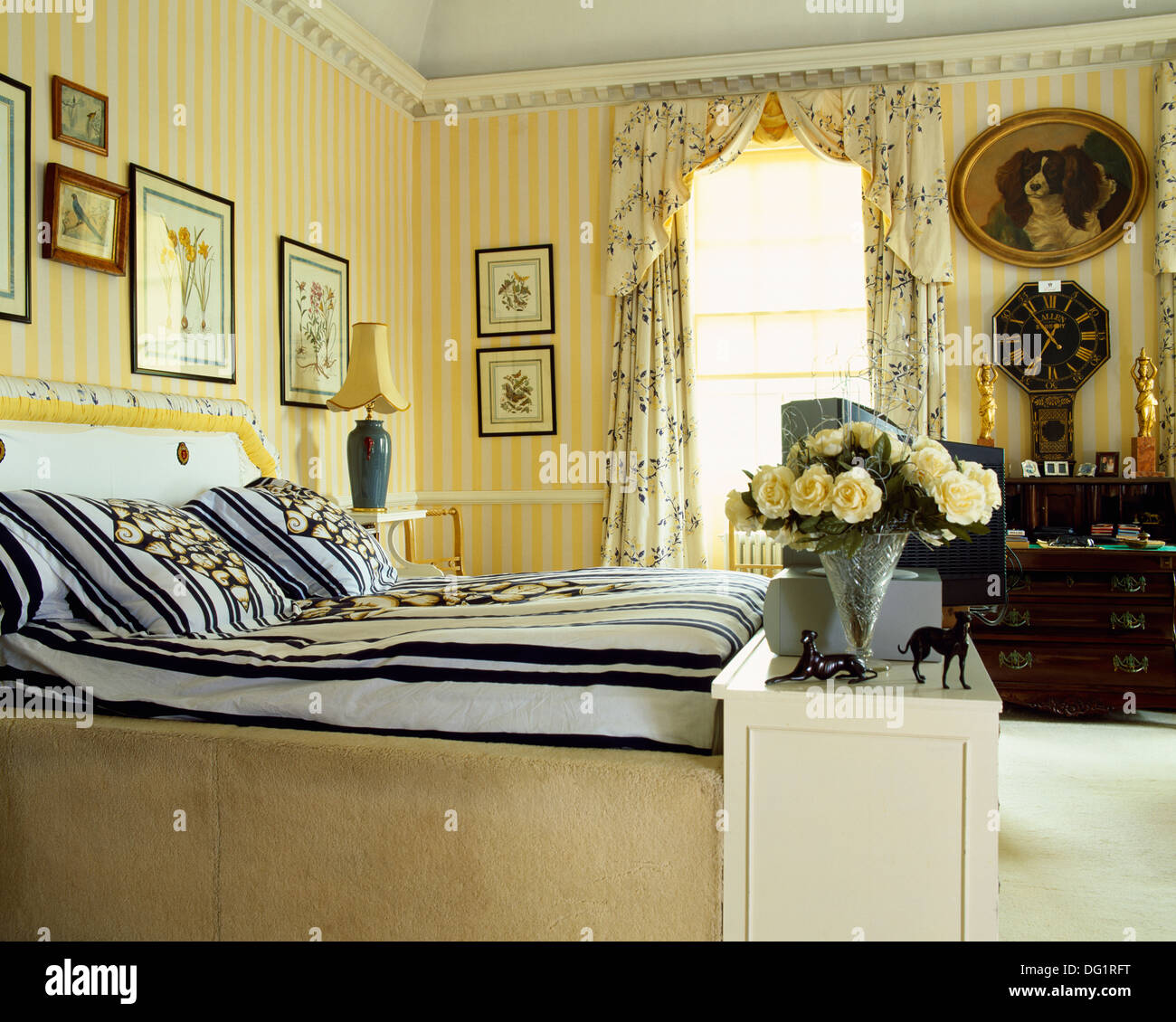 Gelb gestreifte Tapete und floral Gardinen im Schlafzimmer Stadthaus mit  schwarz + weiß gestreiften Bettdecke auf ausgestattete Bett Stockfotografie  - Alamy