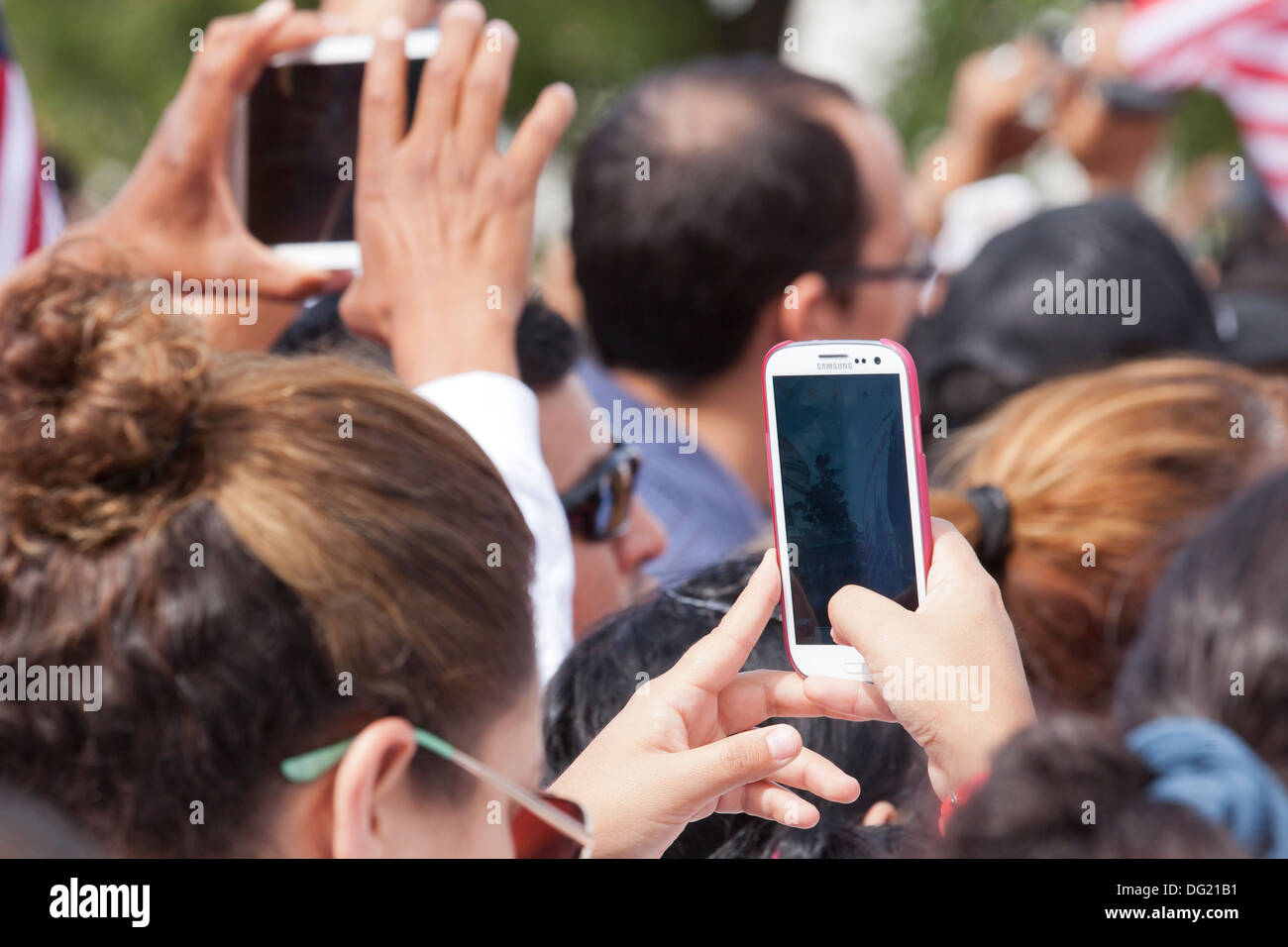 Frau Video taping ein outdoor-Event über Menschenmenge mit Samsung Smartphone Stockfoto
