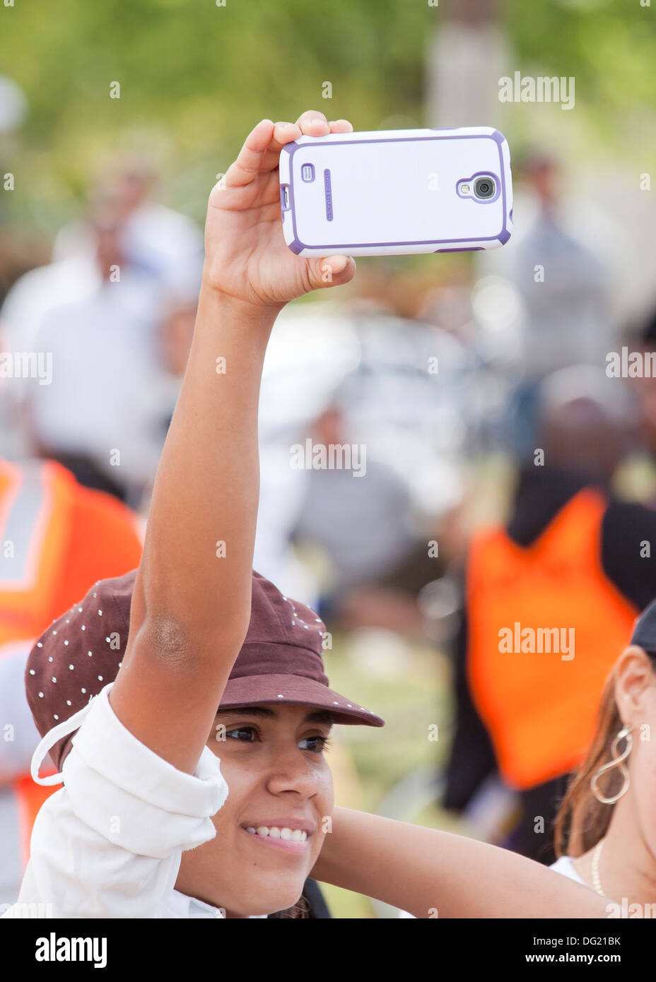 Junge weibliche Video taping mit Smartphone an ein outdoor-event Stockfoto