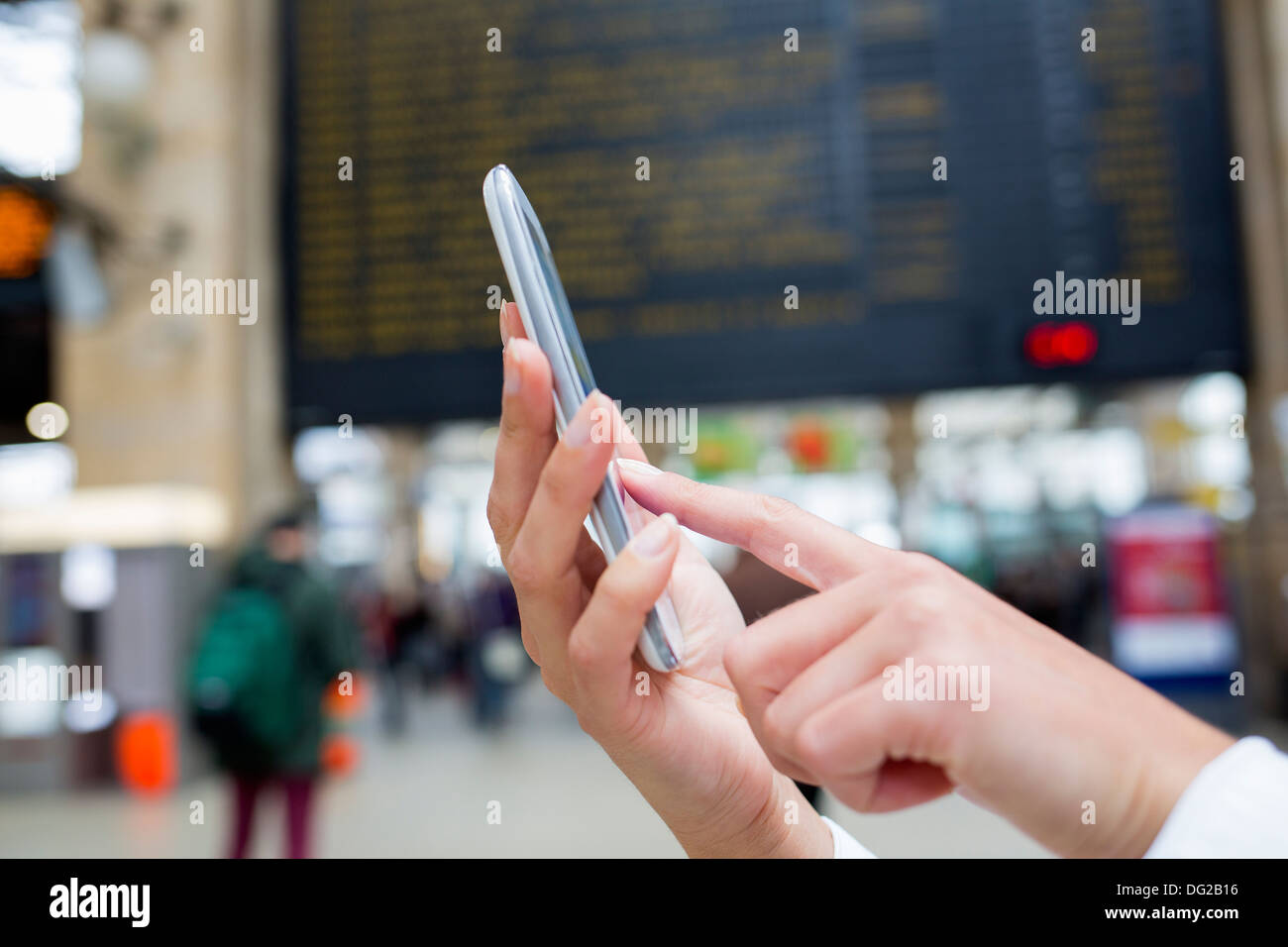 Frau mit ihrem Handy in Halle Bahnhof. Schließen Sie die Hände Stockfoto