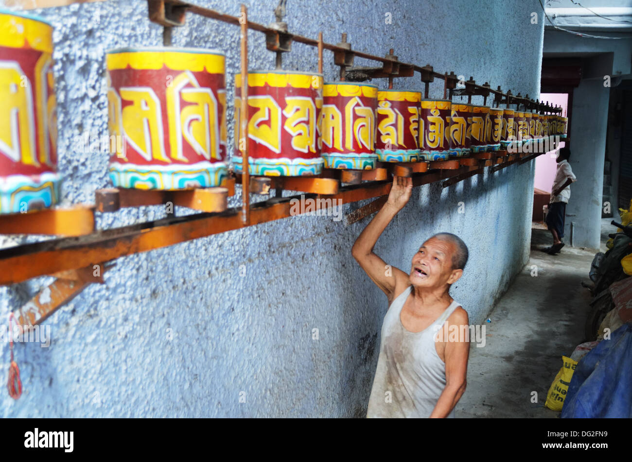 Ein alter tibetischer bewegt sich die Gebetsmühlen in Majnu ka Tilla, eine Kolonie von tibetischen Flüchtlingen in Delhi, Indien Stockfoto