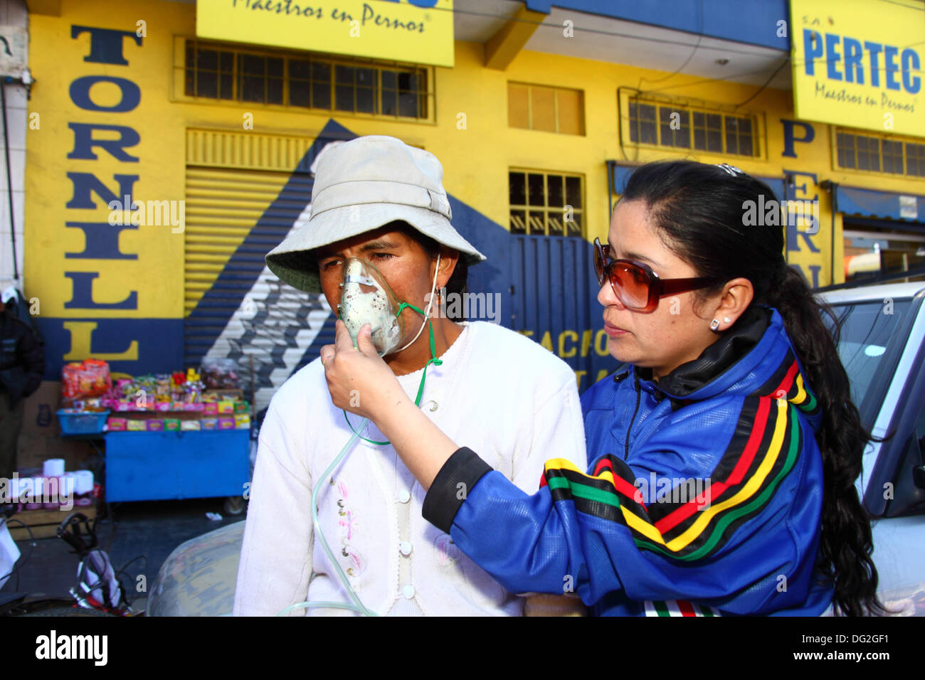 El Alto, Bolivien. Oktober 2013. Ein Wettbewerber erhält Sauerstoff, um sich von den Auswirkungen der Anstrengung in großer Höhe zu erholen, nachdem er ein Cholitas Fahrradrennen für indigene Aymara-Frauen absolviert hat. Das Rennen findet auf einer Höhe von etwas mehr als 4.000 m entlang der Hauptstraßen in El Alto (oberhalb von La Paz) zum bolivianischen Frauentag statt, der gestern Freitag, den 11. Oktober war. Quelle: James Brunker / Alamy Live News Stockfoto