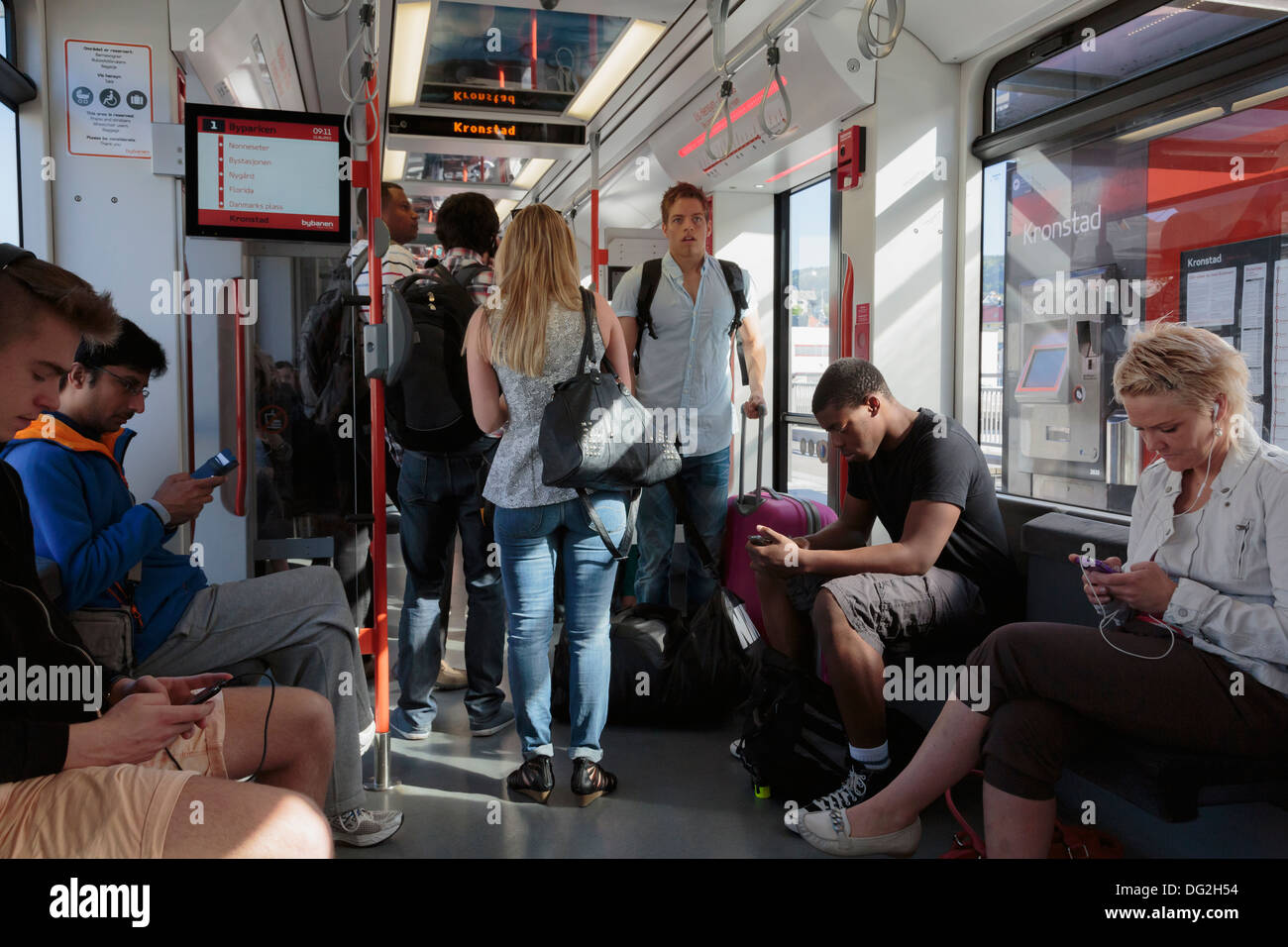 Passagiere, die mit Smartphones und iPods in einem Wagen auf der Hudson-Bergen Light Rail-Nahverkehr in Norwegen Stockfoto