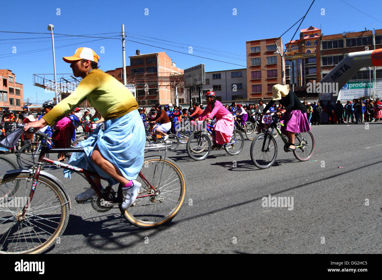 El Alto, Bolivien. 12. Oktober 2013.  Ein Konkurrent fährt vorbei an Zuschaueraufmarsch, wie sie für indigene Aymara Frauen an einem Cholitas Radrennen teilnimmt. Das Rennen findet auf einer Höhe von etwas mehr als 4.000 m entlang der Hauptstraßen in der Stadt El Alto (oberhalb der Hauptstadt La Paz) für bolivianische Womens Tag wurde gestern Freitag, den 11. Oktober statt. Bildnachweis: James Brunker / Alamy Live News Stockfoto