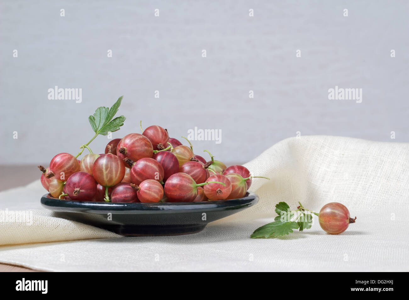 Keramische Tasse mit frischen Stachelbeeren auf hellem Hintergrund Stockfoto