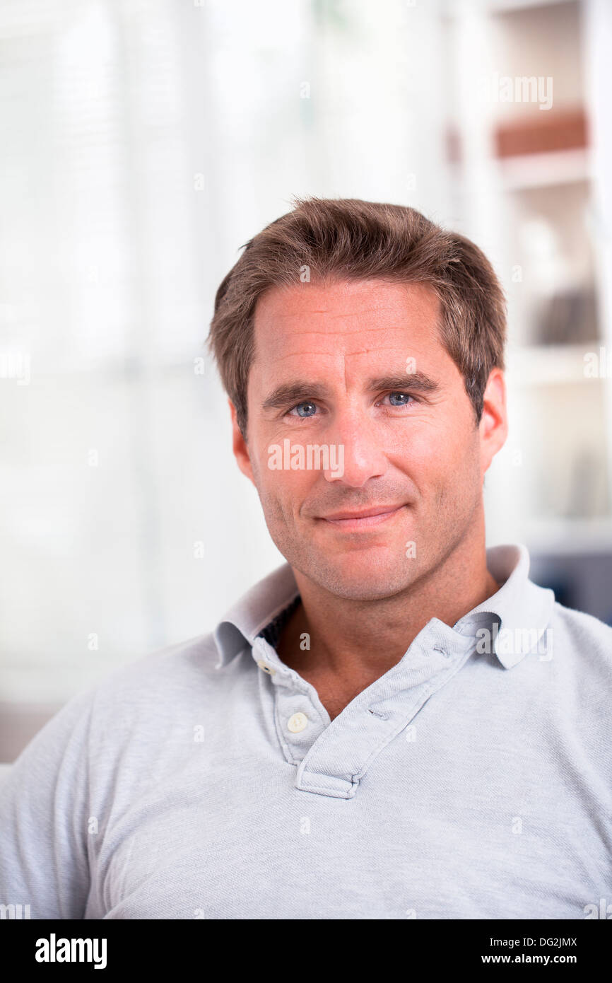 Mann auf Sofa entspannen bei Haus auf der Suche um die Kamera zu Lächeln Stockfoto