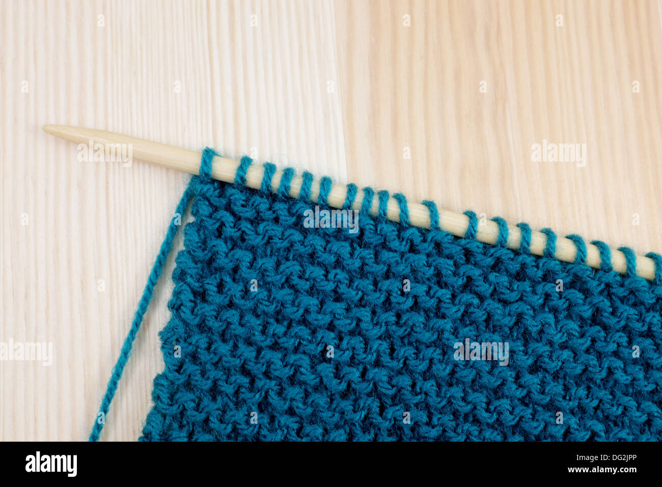 Länge der Strumpfband Nähen im blauen Garn auf Stricknadel, auf hölzernen Hintergrund Stockfoto