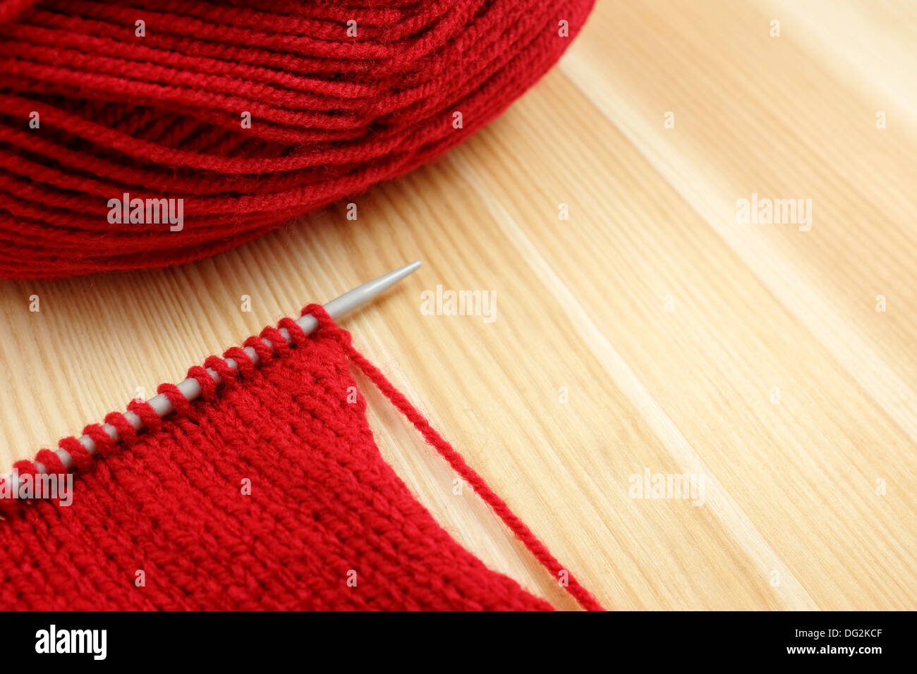 Strumpf Masche auf die Stricknadel mit roten Wollknäuel auf Kiefer board Stockfoto