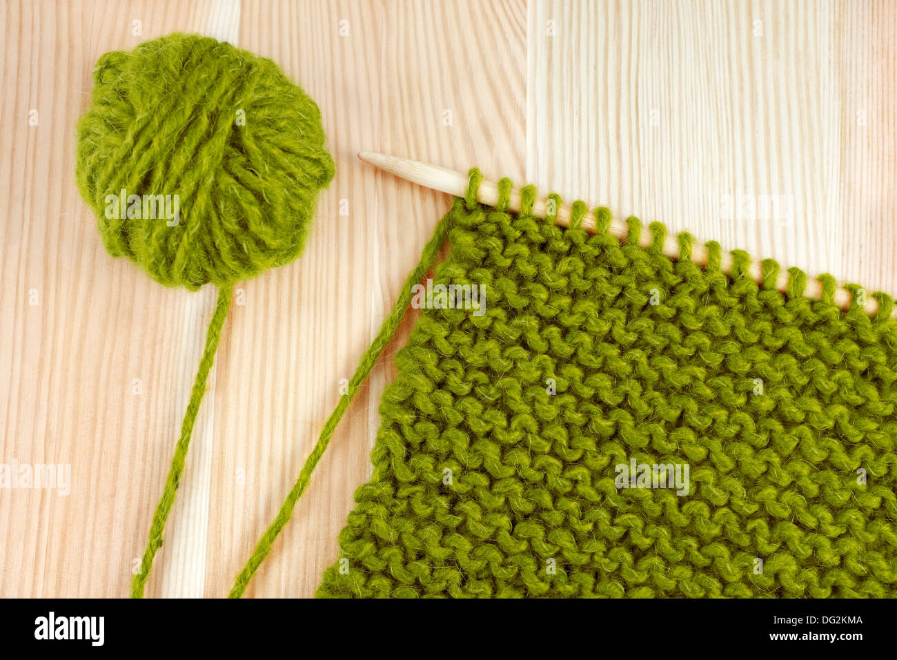 Grüne Kugel Wolle und Strumpfband Maschen auf eine Stricknadel auf Holztisch Stockfoto