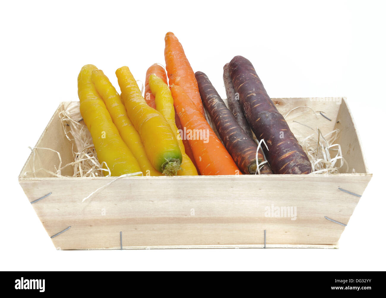 Karotten in verschiedenen Farben in einer Holzkiste auf weißem Hintergrund Stockfoto