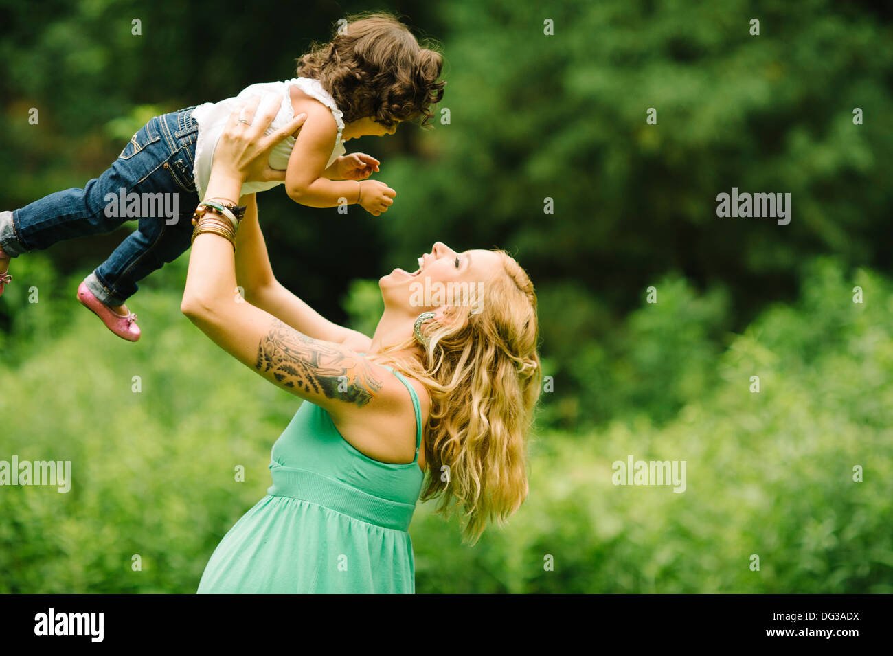 Schwangere Mutter Kind über Kopf anheben Stockfoto