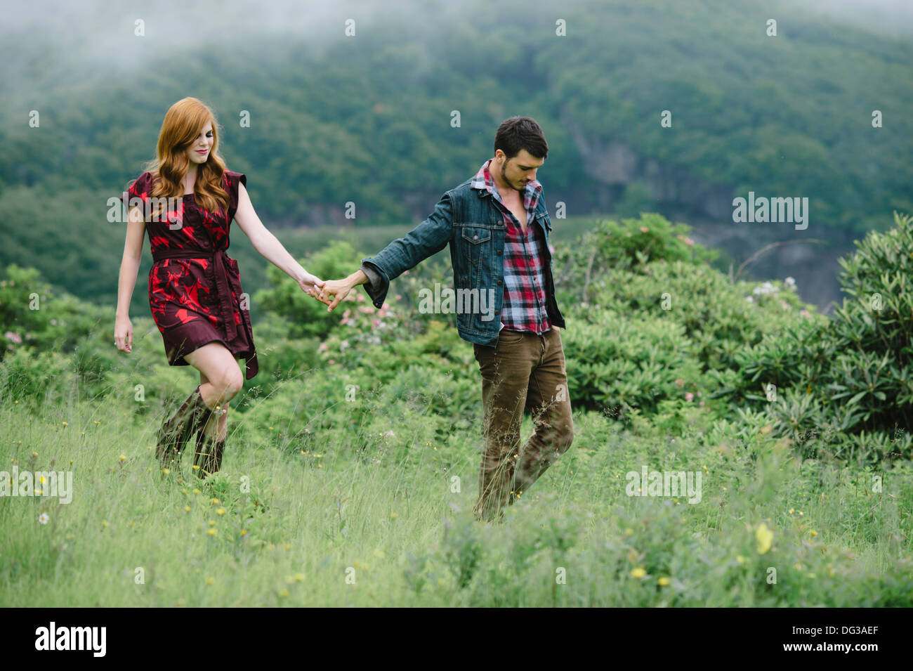 Junges Paar Hand in Hand bei einem Spaziergang durch Feld Stockfoto