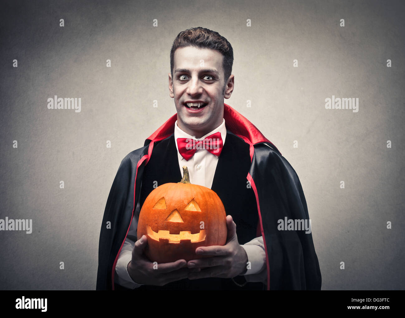 Mann verkleidet als Dracula hält einen Halloween-Kürbis und lächelnd Stockfoto