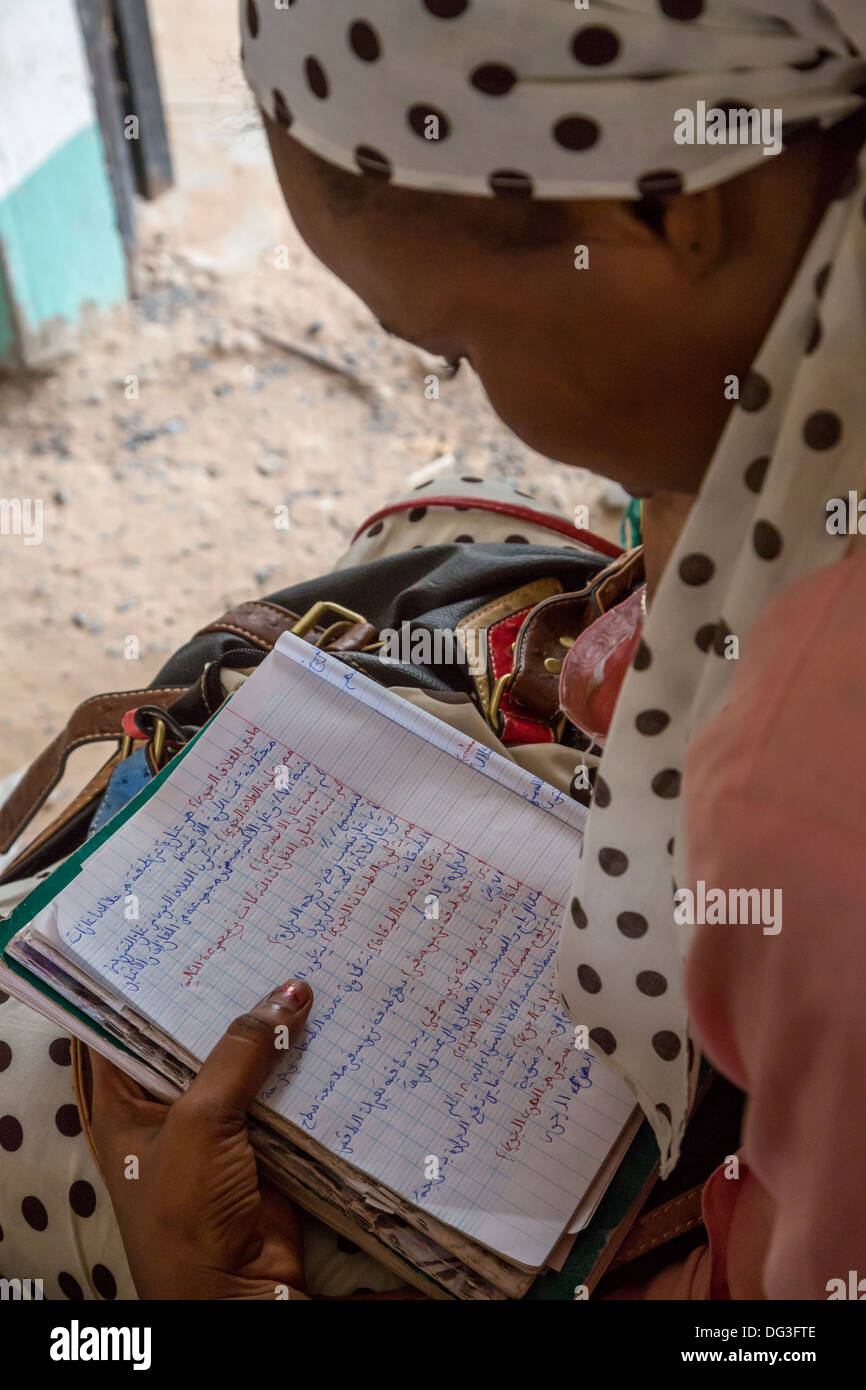 Senegal, Touba. Junge Frau bei der Al-Azhar Institut der islamischen Studien betrachten ihre Arbeitsmappe mit Unterricht in Arabisch geschrieben. Stockfoto