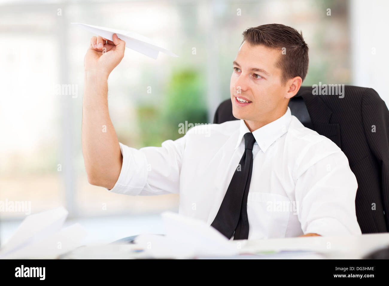 lächelnde Geschäftsmann mit Papierflieger im Büro spielen Stockfoto