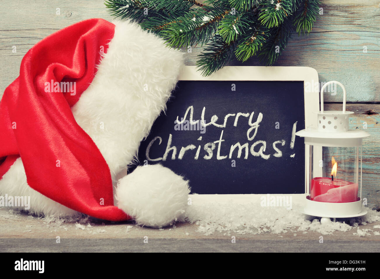 Kerze in die Laterne und gerahmten Tafel mit Weihnachtsmütze auf hölzernen Hintergrund Stockfoto