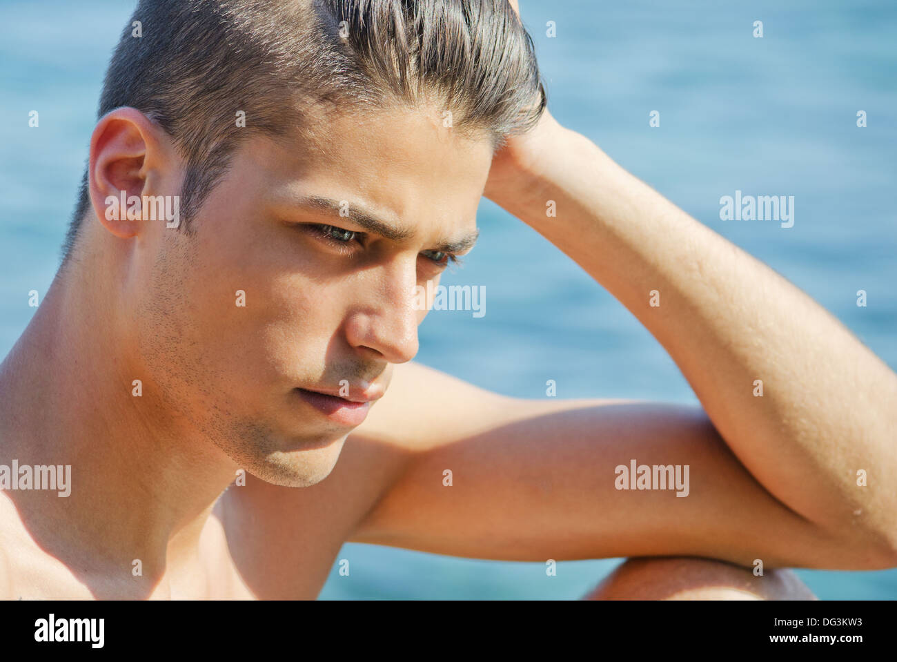 Hübscher junger Mann denken direkt am Meer mit nassen Haaren, hand auf den Kopf. Stockfoto