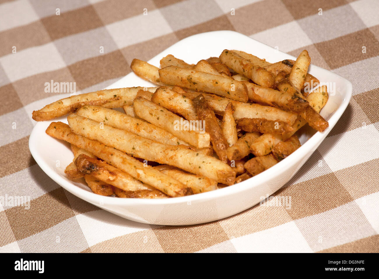 Ein Teller mit erfahrenen Pommes Frites auf einem Tisch Stockfoto
