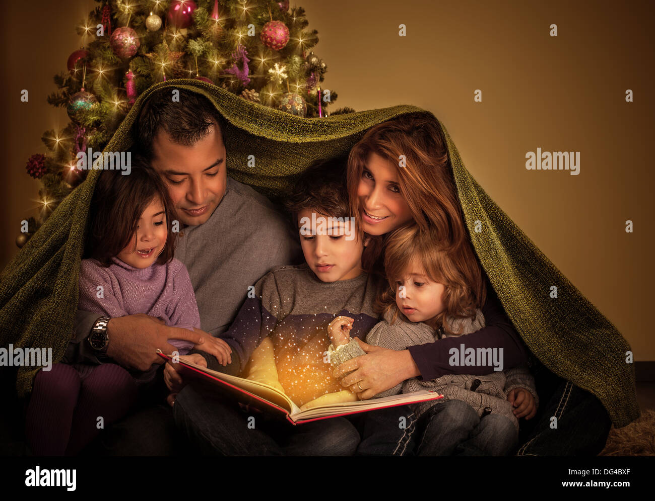 Große Familie lesen interessante magische Geschichte in Heiligabend, glückliche Eltern mit fröhlichen Kindern mit Decke bedeckt. Stockfoto