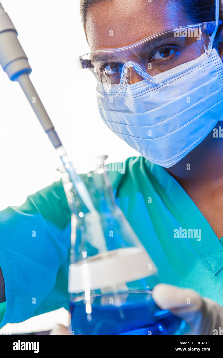 Asiatische medizinische oder wissenschaftliche Forscherin oder Arzt mit Hilfe einer Pipette & konischen Kolben blaue Lösung in einem Labor Stockfoto