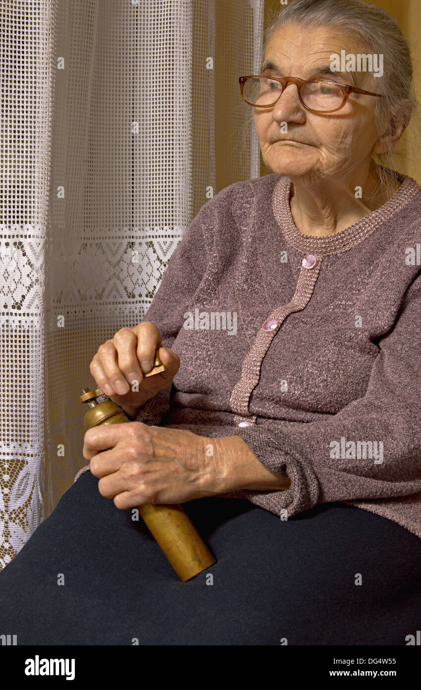 Porträt einer alten Frau mit Mahlwerk in Händen. Träumen der Vergangenheit. Stockfoto