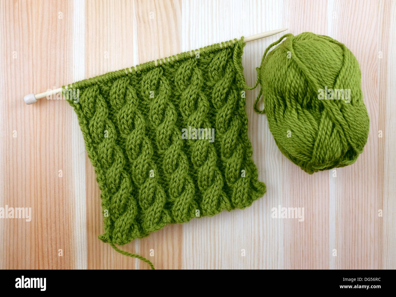 Reiche grüne gewickelte Seil Kabel Masche stricken mit einem Ball aus Wolle auf woodgrain Stockfoto