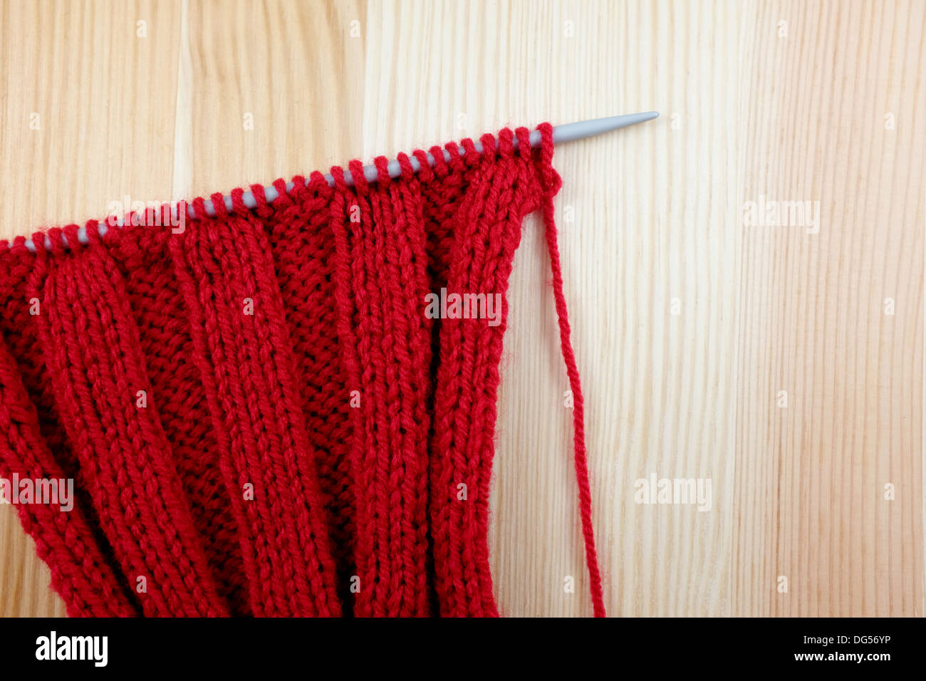 Stricken auf der Nadel im Rib-Stitch auf Holz Hintergrund rot Stockfoto