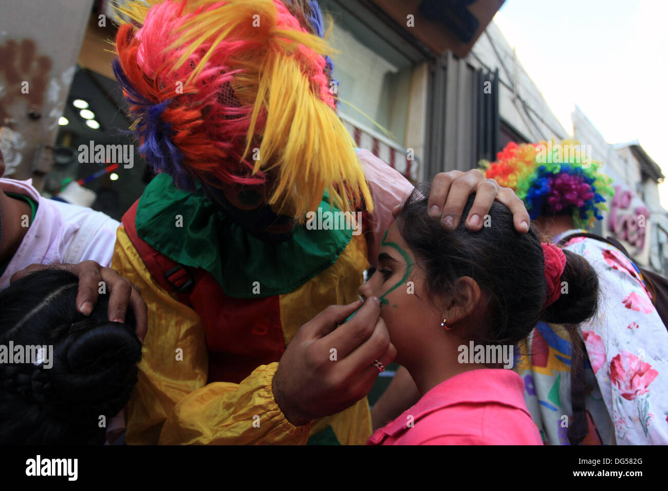 Ramallah, Westjordanland, Palästinensische Gebiete. 14. Oktober 2013. Palästinensische Clowns zeichnen auf Kindergesichter auf einem Wochenmarkt vor der muslimischen fest Eid al-Adha in der Westbank Ramallah am 14. Oktober 2013. Eid al-Adha (das Festival von Opfern) wird als eine Erinnerung an Abrahams Bereitschaft, seinen Sohn für Gott Opfern während der moslemischen Welt gefeiert und Kühen, Kamelen, Ziegen und Schafe geschlachtet werden traditionell auf der heiligste Tag Credit: Issam Rimawi/APA Images/ZUMAPRESS.com/Alamy Live News Stockfoto