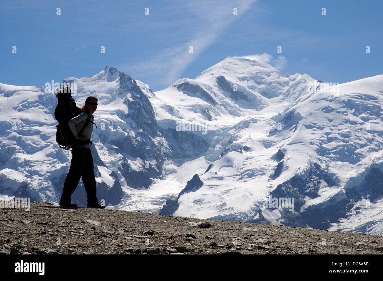 Wandern in den französischen Alpen Mutter mit ihrem Kind im Tragetuch mit dem Mont Blanc hinter Stockfoto