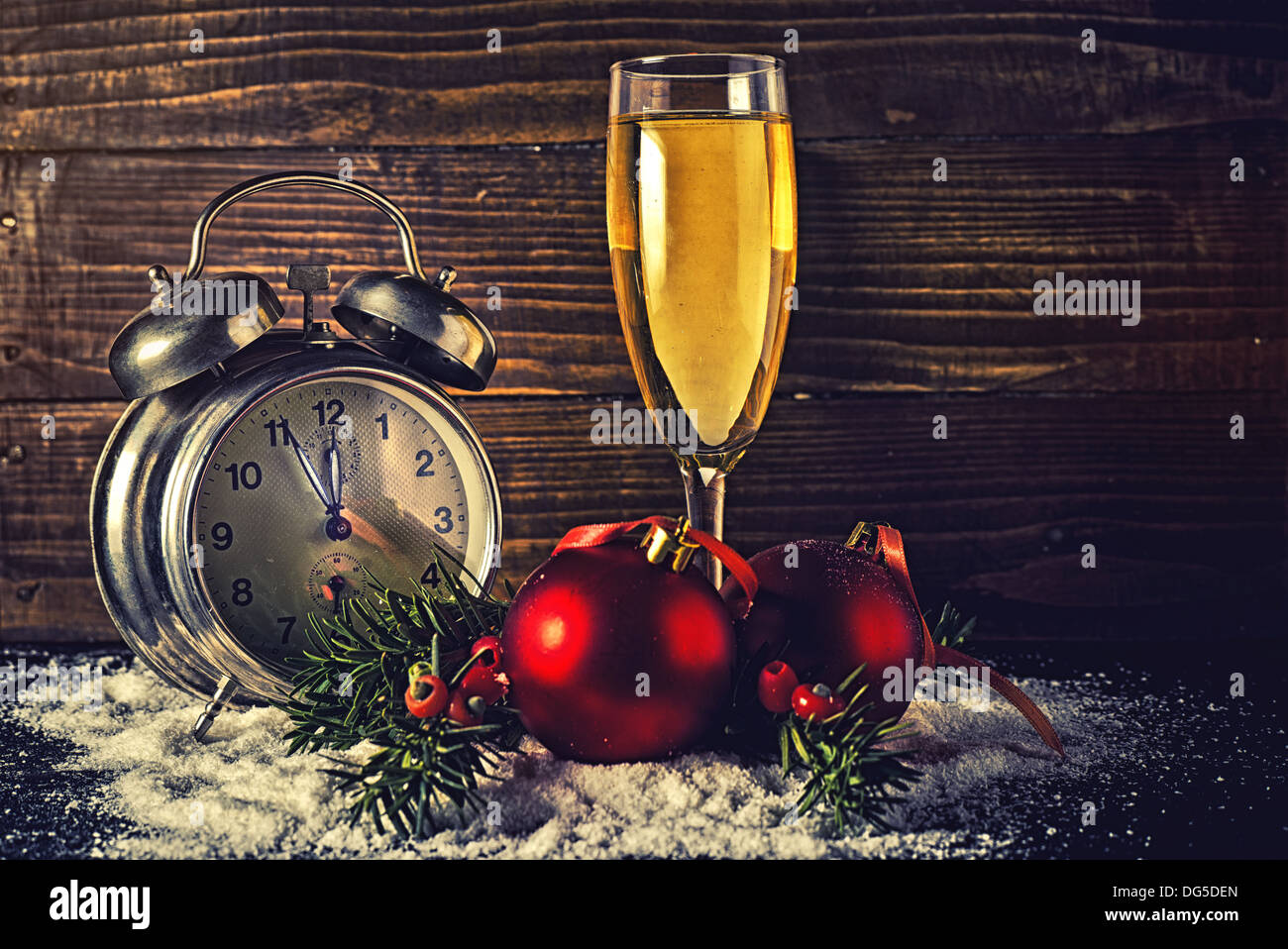 Weihnachtskugeln, ein Glas Champagner und Vintage Uhr fünf Minuten vor Mitternacht an Silvester. Stockfoto