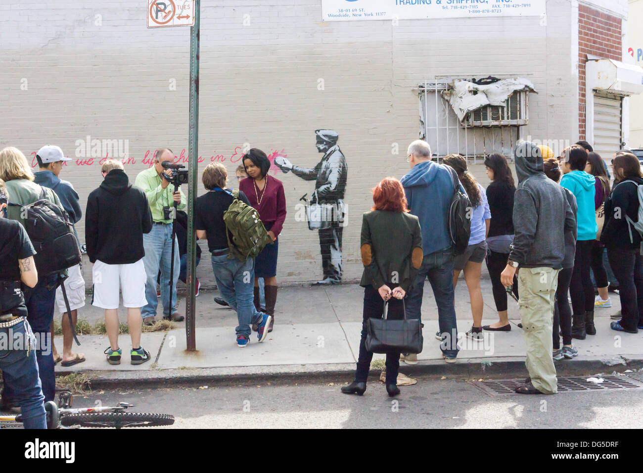 New York, USA. 14. Oktober 2013. Streetart-Fans strömen in Woodside Stadtteil Queens in New York auf Montag, 14. Oktober 2013, der vierzehnte Ausgabe von Banksy-Graffiti-Kunst, "Was wir im Leben Echos in der Ewigkeit tun" zu sehen. Die schwer fassbare Streetart-Künstler schafft Werke rund um die Stadt jeden Tag im Laufe des Monats Oktober begleitet durch eine satirische aufgezeichnete Nachricht, die Sie hören können telefonisch unter der Nummer 1-800-656-4271 gefolgt von # und die Anzahl der Kunstwerke.  (© Richard B. Levine) Bildnachweis: Richard Levine/Alamy Live-Nachrichten Stockfoto