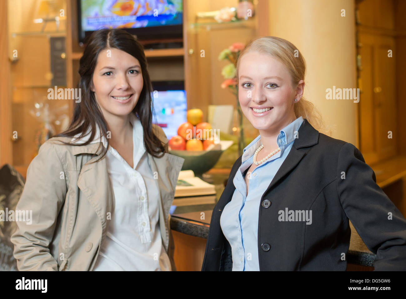 Zwei schöne stilvolle Frauen Freunde stehen zusammen in ein Luxus-Innenraum mit einem freundlichen Lächeln in die Kamera schaut Stockfoto