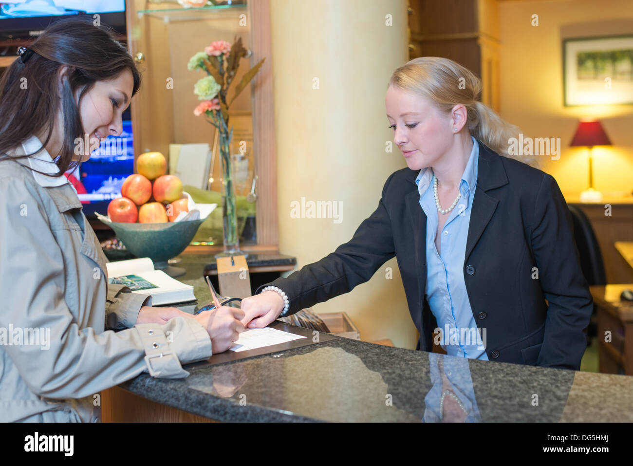 Schöne freundliche blonde Frau auf einer Hotel-Rezeption Stockfoto