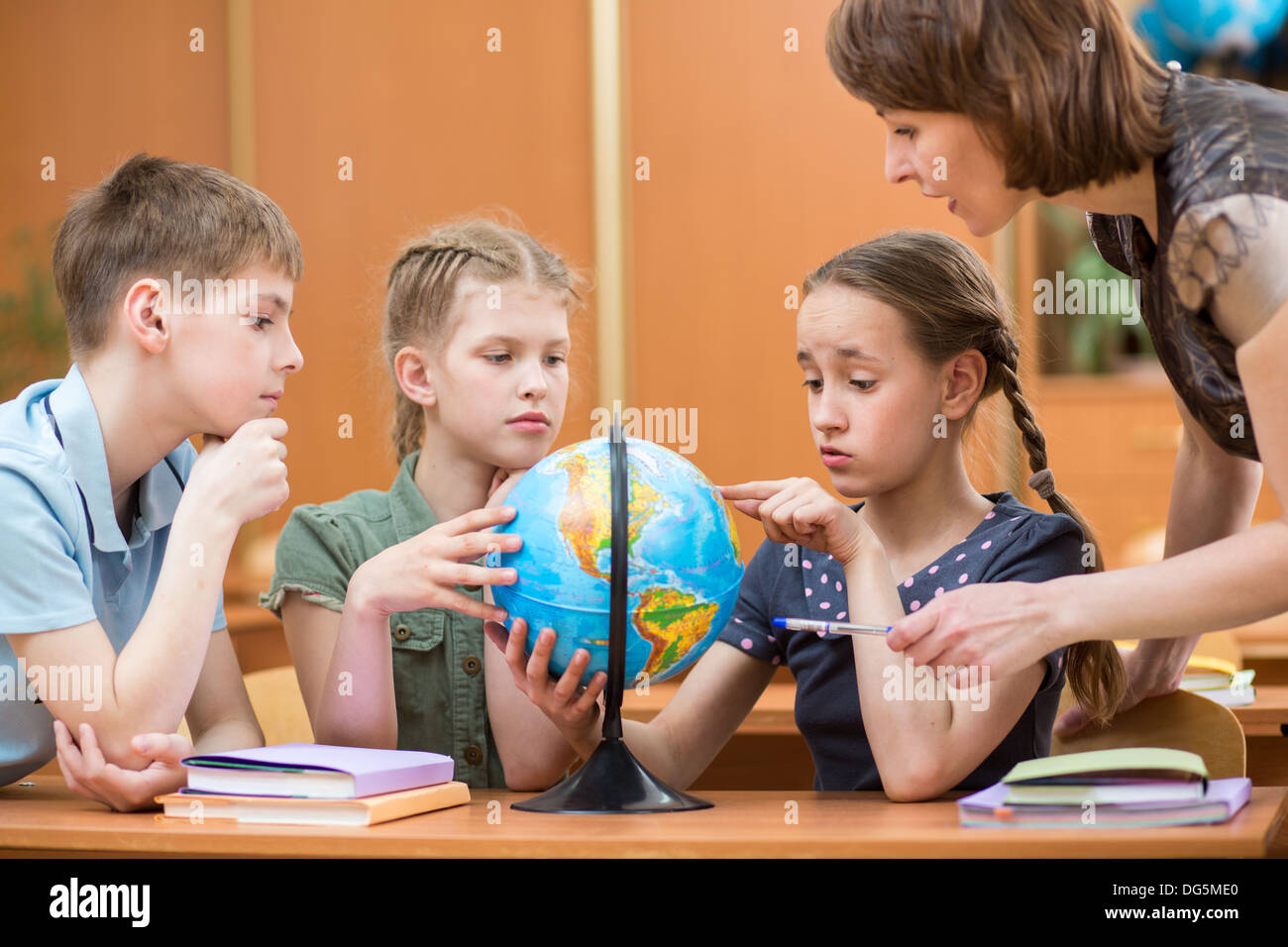 Schulkinder studieren einen Globus zusammen mit Lehrer Stockfoto