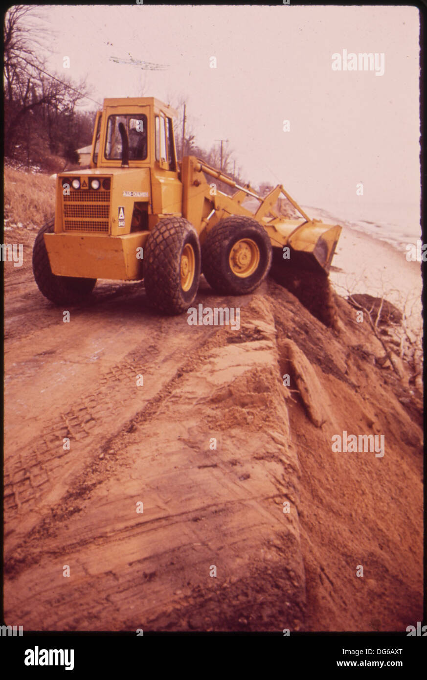 Ein Heeresbagger wird verwendet, um losen Schmutz entlang des Lake Shore Drive anzuhäufen, um das Ufer zu verstärken, das durch das Seewasser erodiert wurde. Diese Arbeiten sind Teil der Bemühungen, die Infrastruktur zu schützen und weitere Schäden durch Erosion zu verhindern. Stockfoto Ein Heeresbagger wird verwendet, um losen Schmutz entlang des Lake Shore Drive anzuhäufen, um das Ufer zu verstärken, das durch das Seewasser erodiert wurde. Diese Arbeiten sind Teil der Bemühungen, die Infrastruktur zu schützen und weitere Schäden durch Erosion zu verhindern. Stockfoto