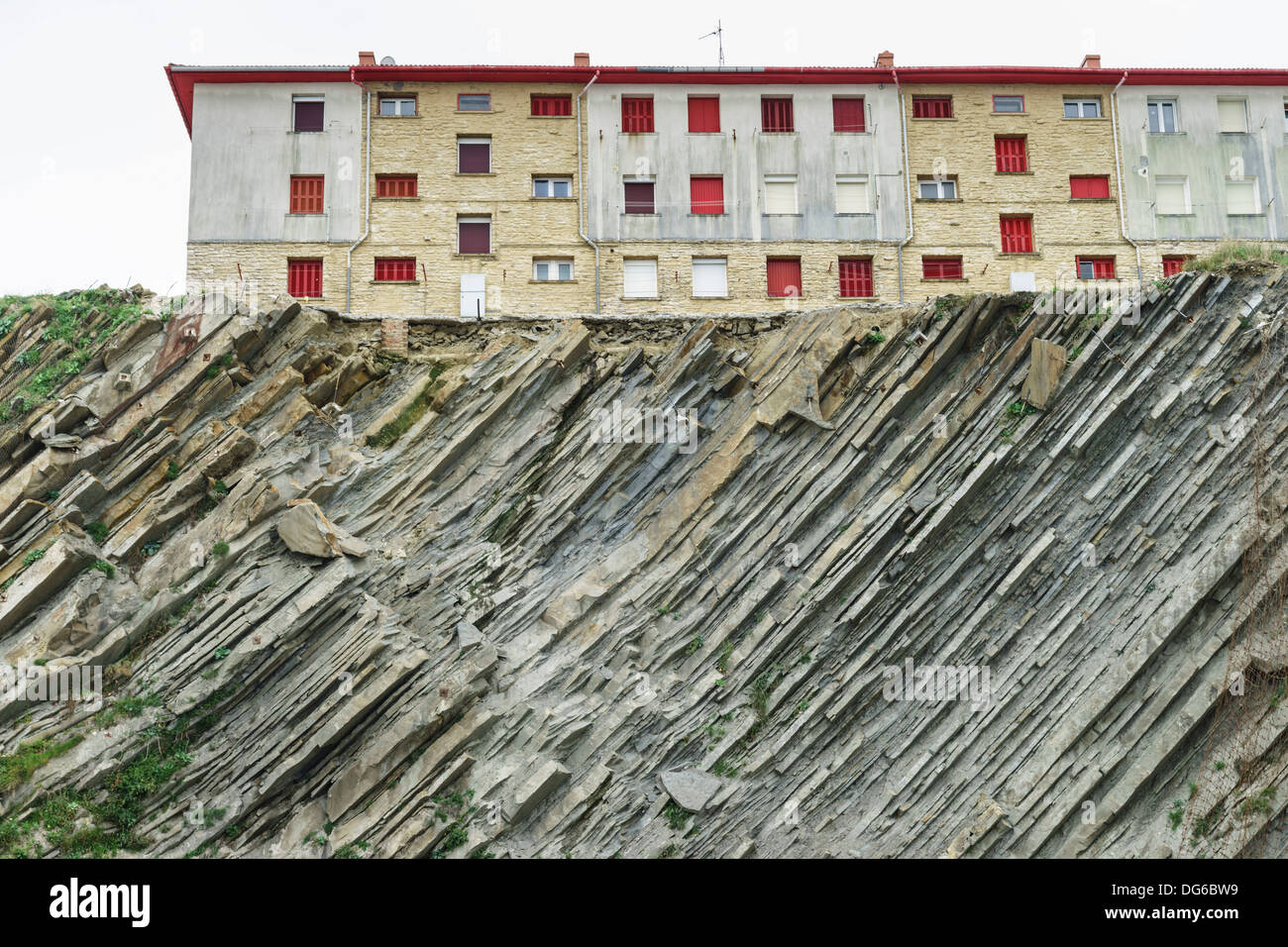Nordspanien Fischerdorf und Kurort Getaria. Schiefer Klippen und Gesteinsschichten unter modernen Gehäuse mit Anti-Möwe Net. Stockfoto