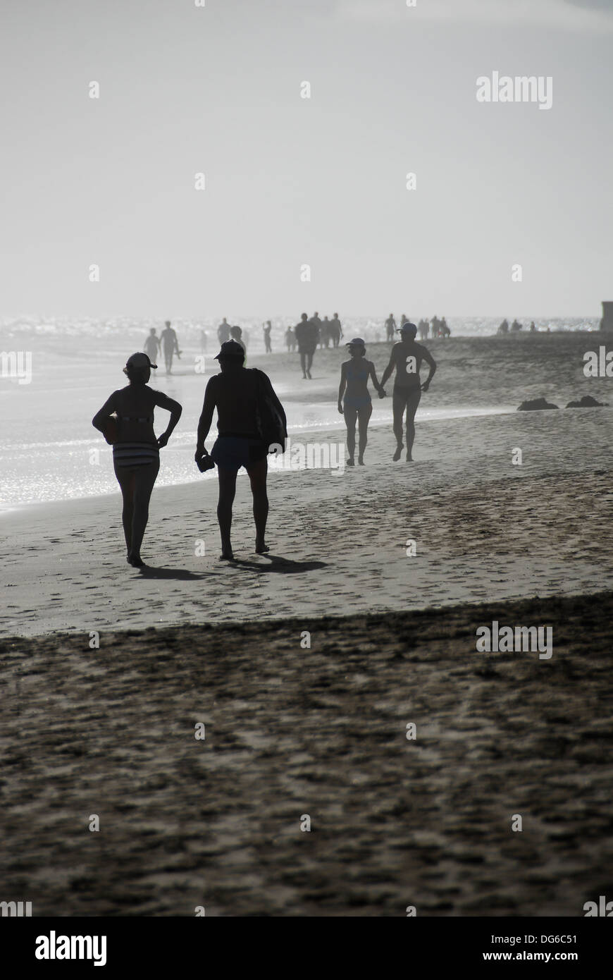 Paare, die zu Fuß und Hand in Hand am Strand Stockfoto
