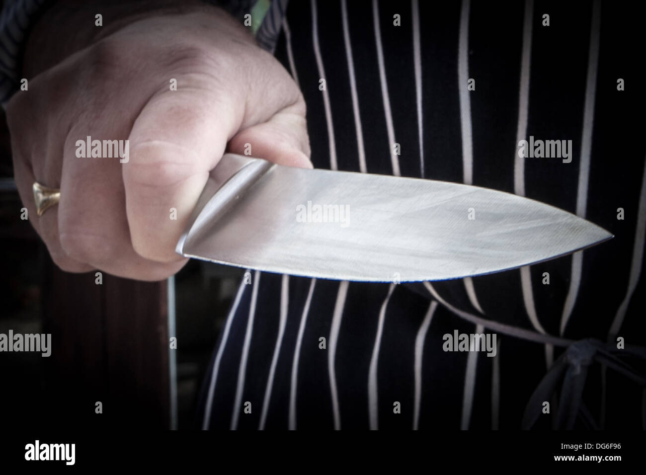 Mann trägt eine Köche Schürze mit einem Küchenmesser Stockfoto